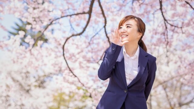 桜の木の下で新生活を応援する女性のイメージ画像