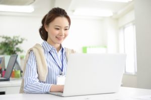 ノートパソコンで仕事をする女性社員のイメージ画像